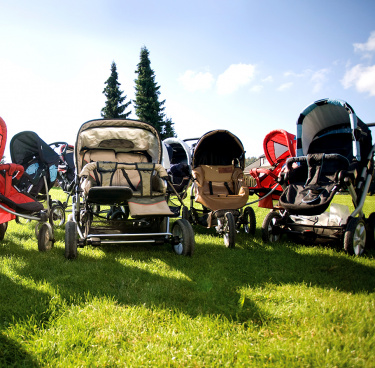 Kinderwagen auf dem Rasen vor blauem Himmel