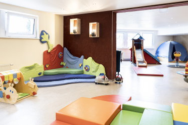 Spielzimmer mit Kletterlandschaft und Rutsche für Babys und Polsterelementen für Eltern